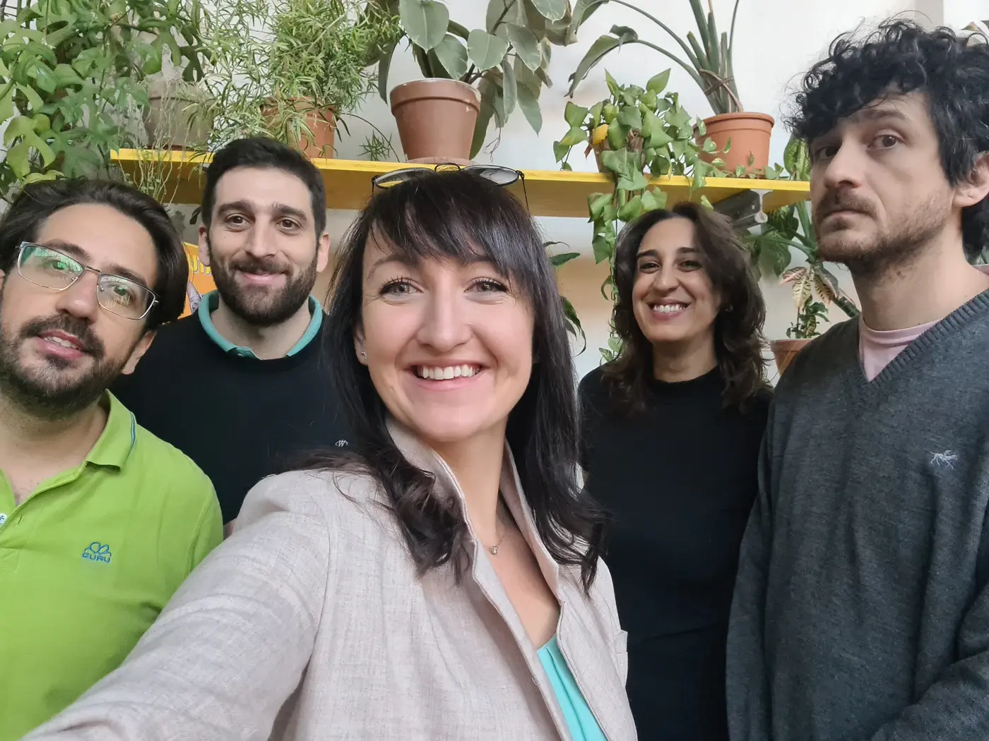 Five Patio members taking a group selfie among indoor plants