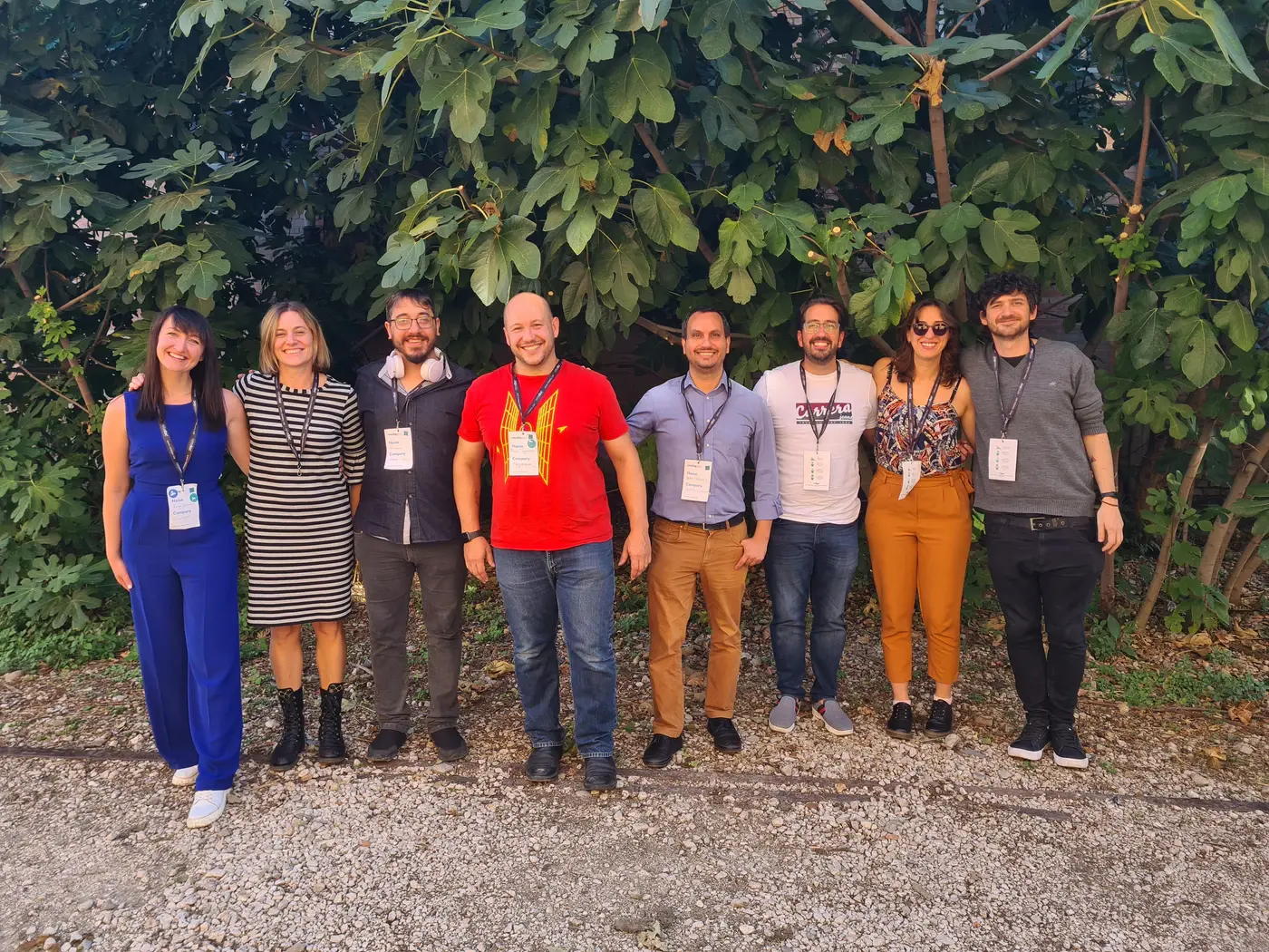 Patio members standing outdoors in front of leafy trees